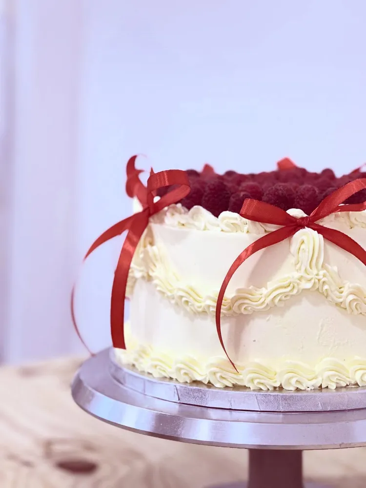 Vintage cake blanca con frambuesas y lazos rojos